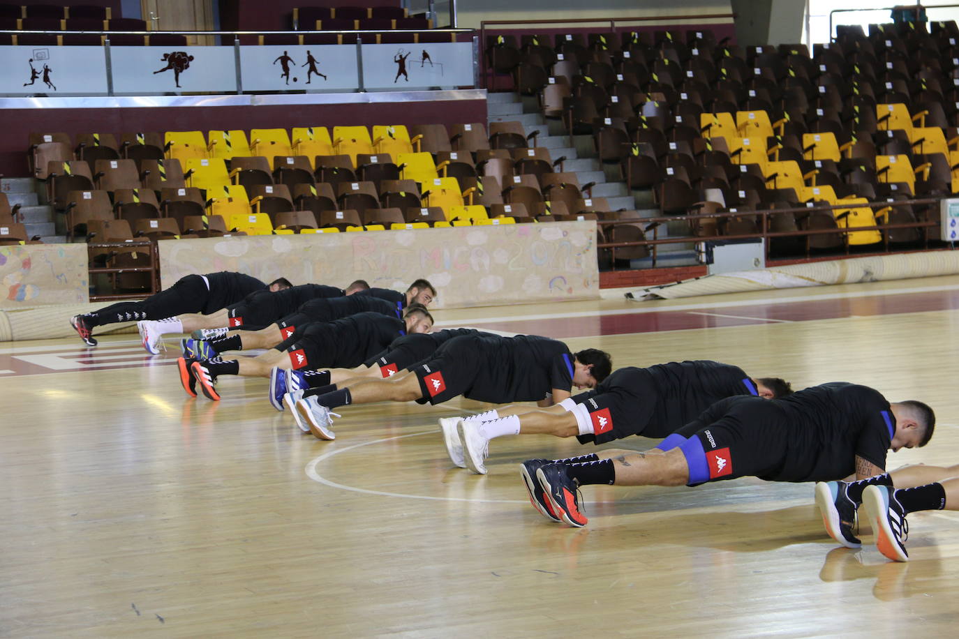 La plantilla del Ademar realiza flexiones en medio de la cancha del Palacio de los Deportes. 