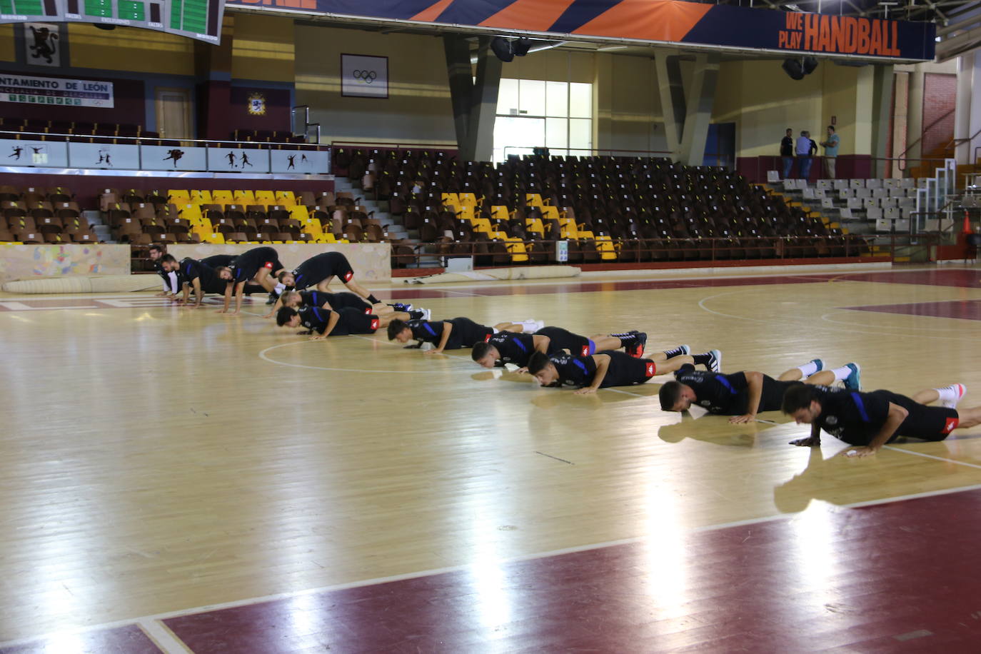 La plantilla del Ademar realiza flexiones en medio de la cancha del Palacio de los Deportes. 