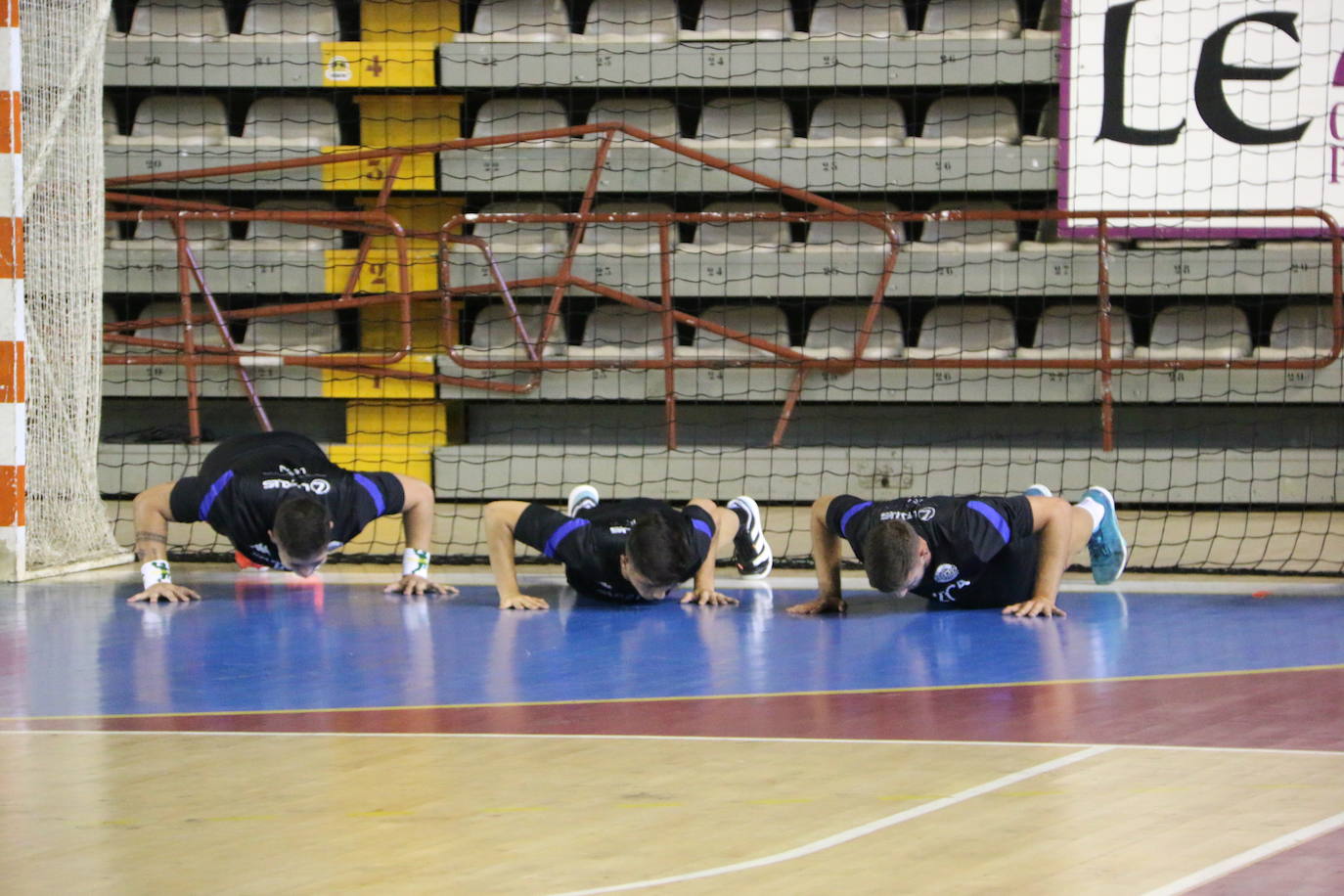 La plantilla del Ademar realiza flexiones en medio de la cancha del Palacio de los Deportes. 