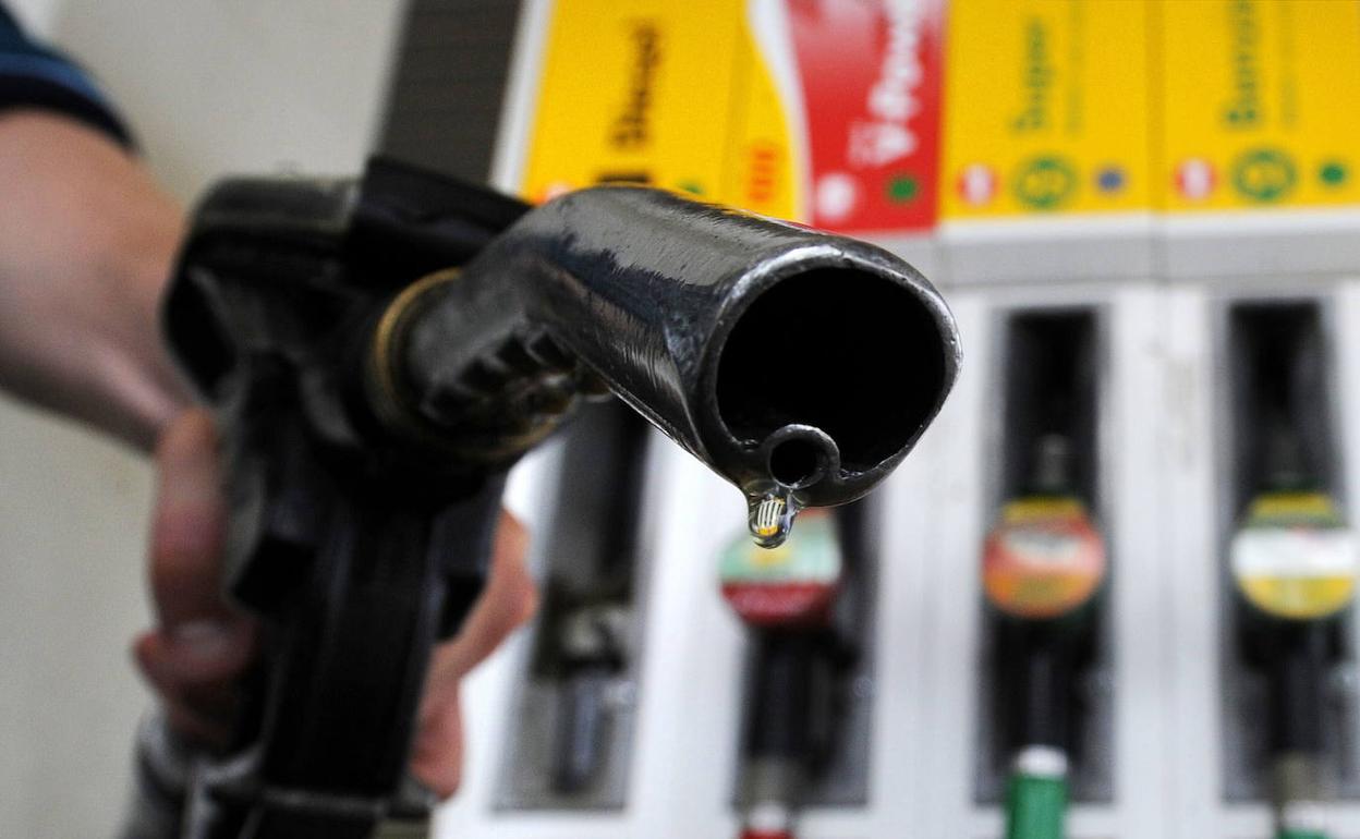 Un hombre junto a un surtidor en una gasolinera. 