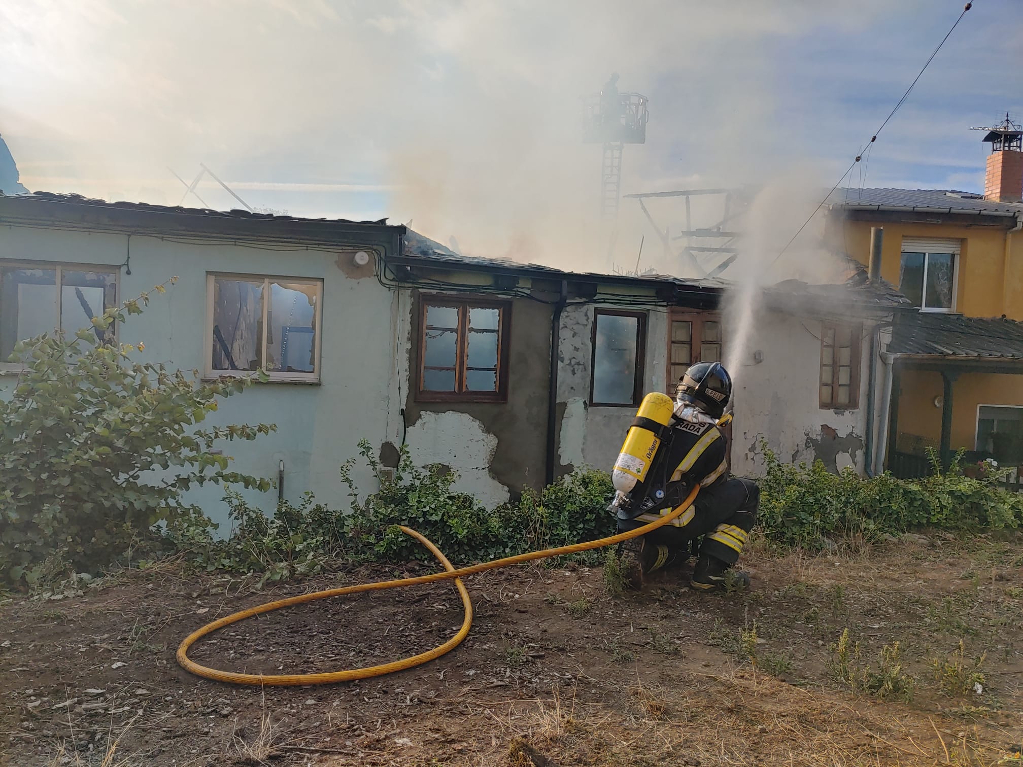 Los Bomberos de Pofnerrada trabajan en la extinción de un intenso fuego que se originaba en una casa de Villalibre y de lque todavía se desconocen sus causas