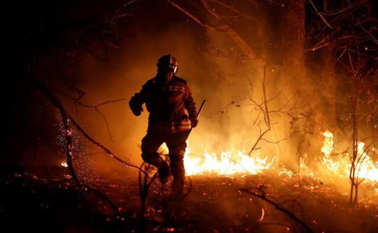 Un brigadista de Castilla y León lucha contra un incendio forestal durante la noche enj una imagen de archivo.