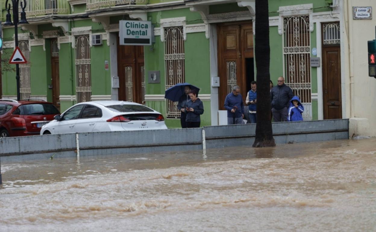 Una valla provisional trata de contener el agua en una calle de Torrent.