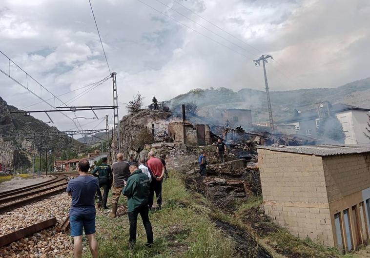 Los bomberos apagan el fuego en la zona de chabolas junto a las vías del tren en Santa Lucía de Gordón.