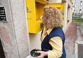 Imagen de archivo de una cartera recogiendo el correo de un buzón.