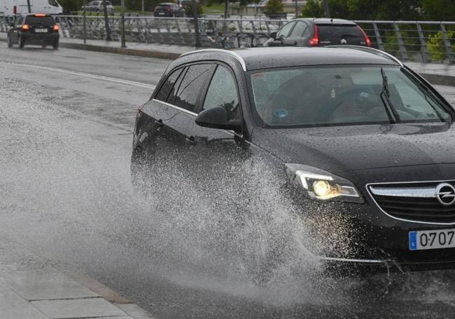 Un coche pasa sobre un charco de lluvia