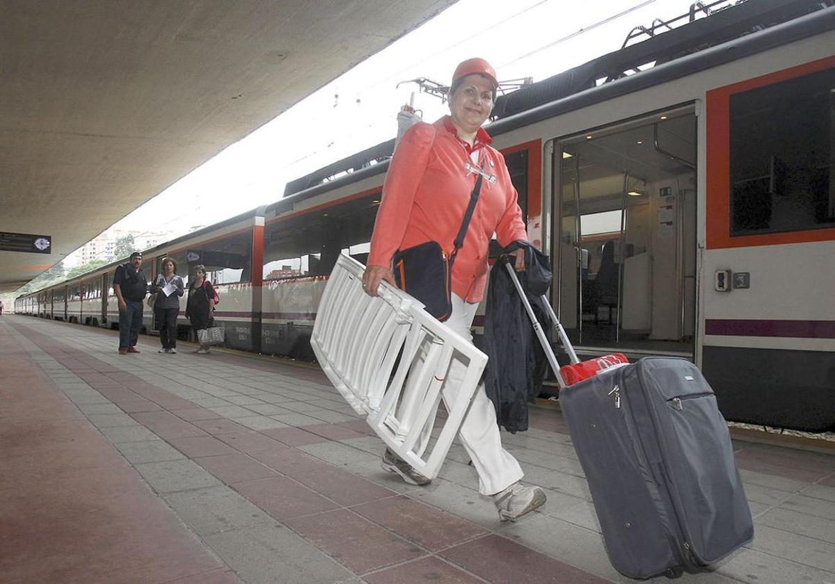 Una mujer camina rumbo a la playa tras descender del tren.