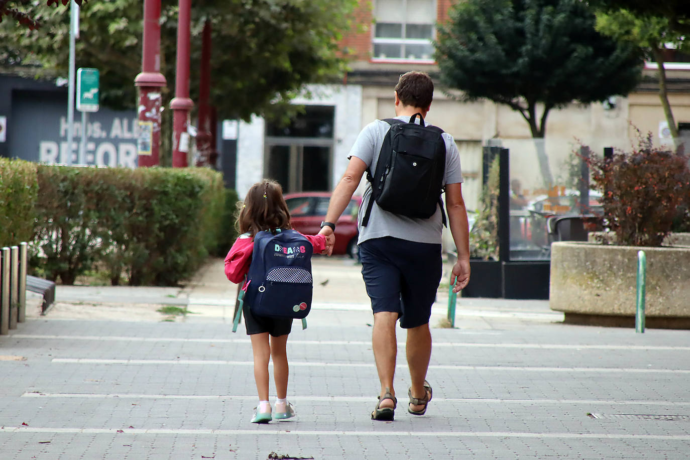 Un padre acude con su hija al colegio en el primer día de curso.