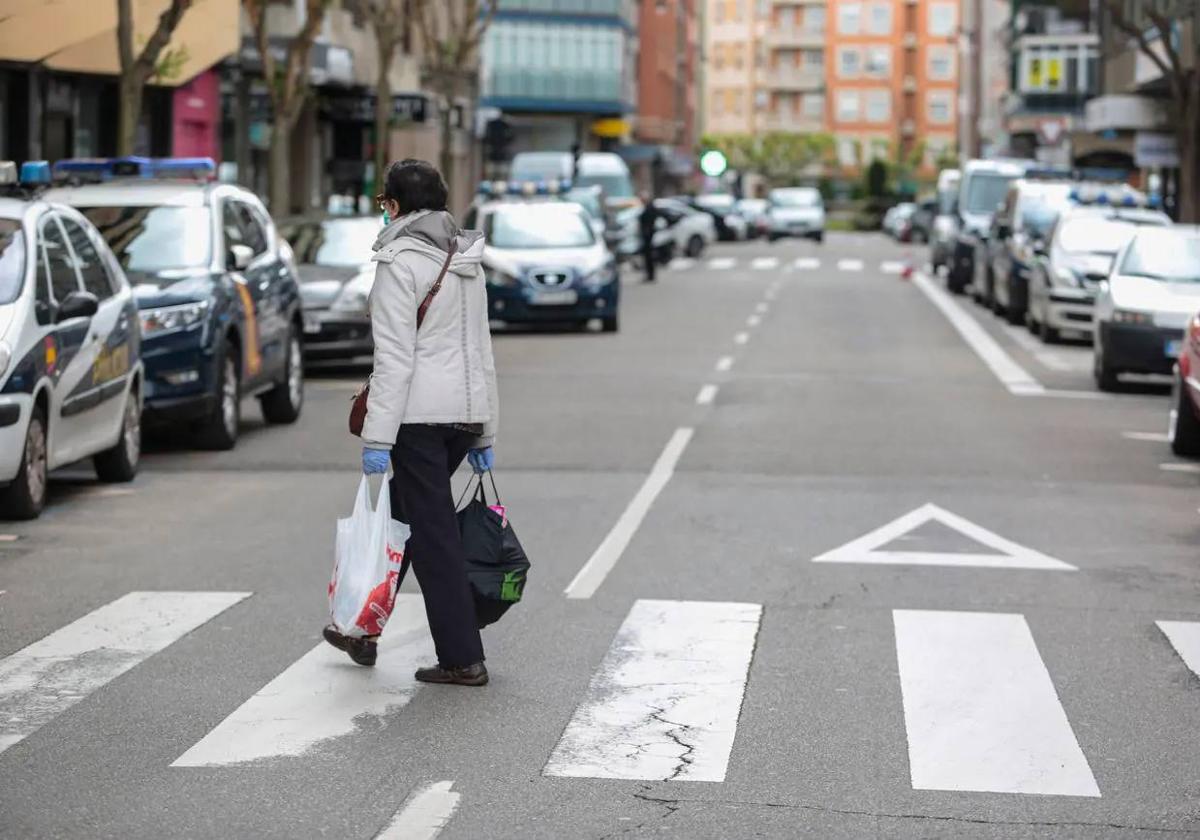 Imagen de una mujer cruzando un paso de peatones en León.