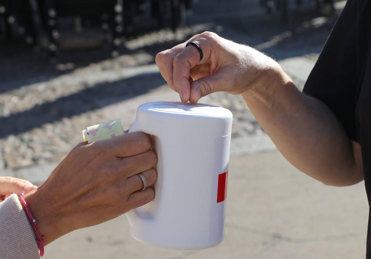 Una persona deposita un donativo en una de las huchas de Cruz Roja.