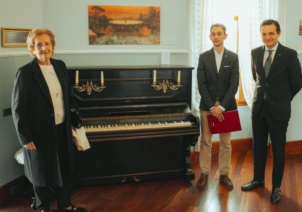 Emilia Fernández Díez, donante, Carlos Varela, conservador jefe del Museo Casa Botines Gaudí y Raúl Fernández Sobrino, director del Museo, posan con el piano colocado en la recreación de la vivienda.