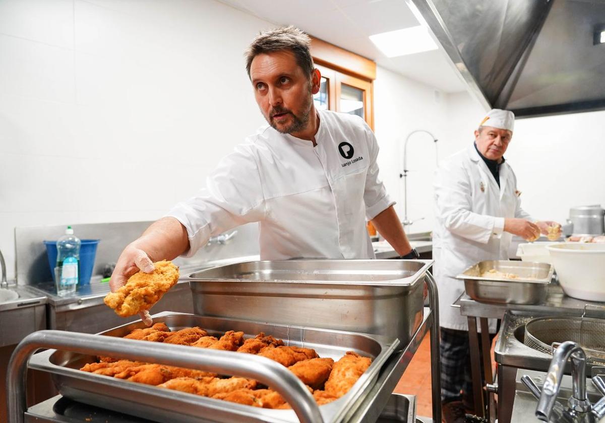 Juanjo Losada coloca un filete de pollo en una bandeja en la cocina del comedor social de Asleca.