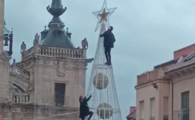 Una persona llega a la cima del árbol de Navidad, mientras la otra sigue subiendo. 