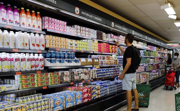 Un consumidor comprando yogures en un supermercado. 