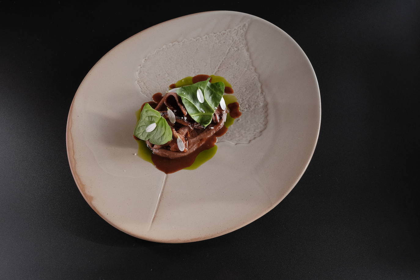 Lengua de buey en salsa de posta negra cartagenera, hongos escabechados en vinagre de plátano y cremoso de semillas de orejero.