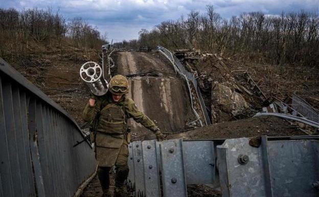 Un soldado ucraniano carga con un lanzamisiles al atravesar uno de los puentes de acceso de Bajmut destruido por los bombardeos rusos./AFP