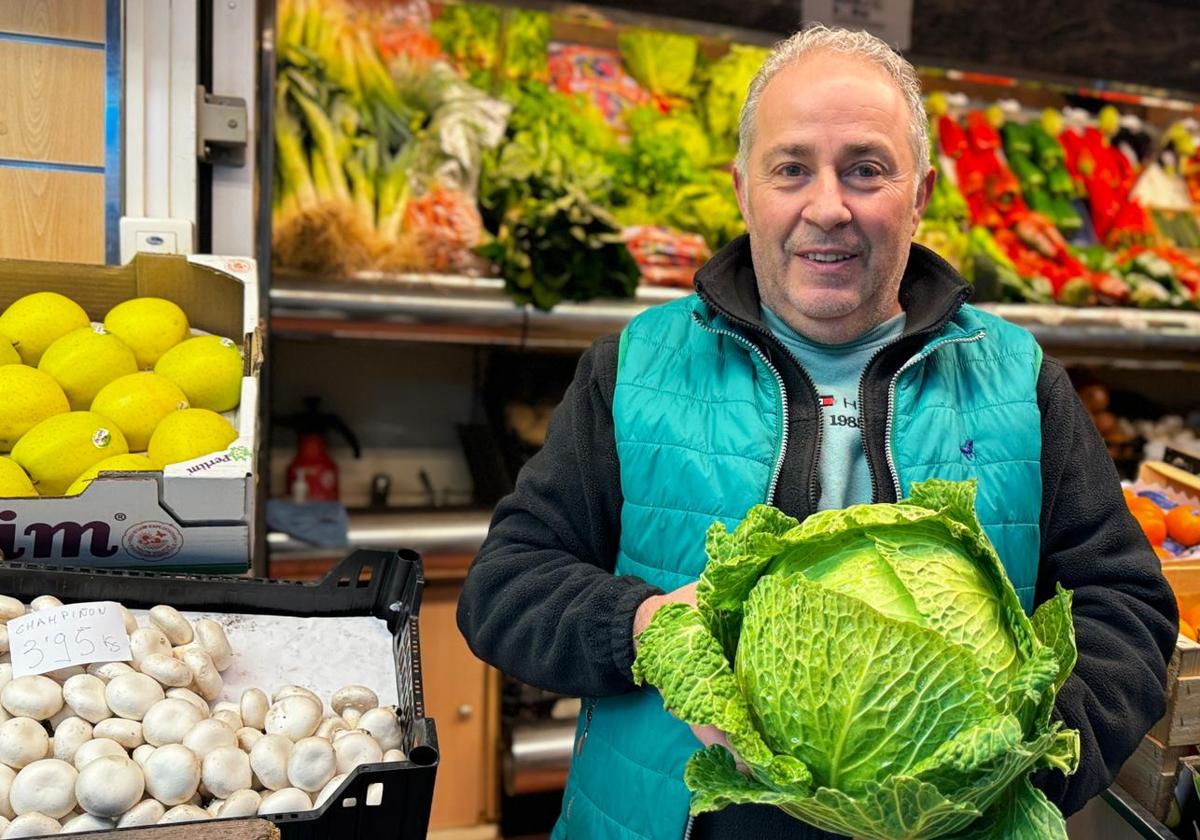 Tomás de la Rosa en su frutería con un repollo.