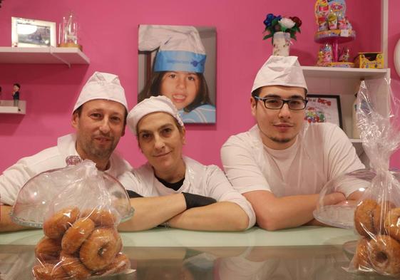 Ángel, Nieves y Rubén en el mostrador de la pastelería con una foto de Lucía al fondo.