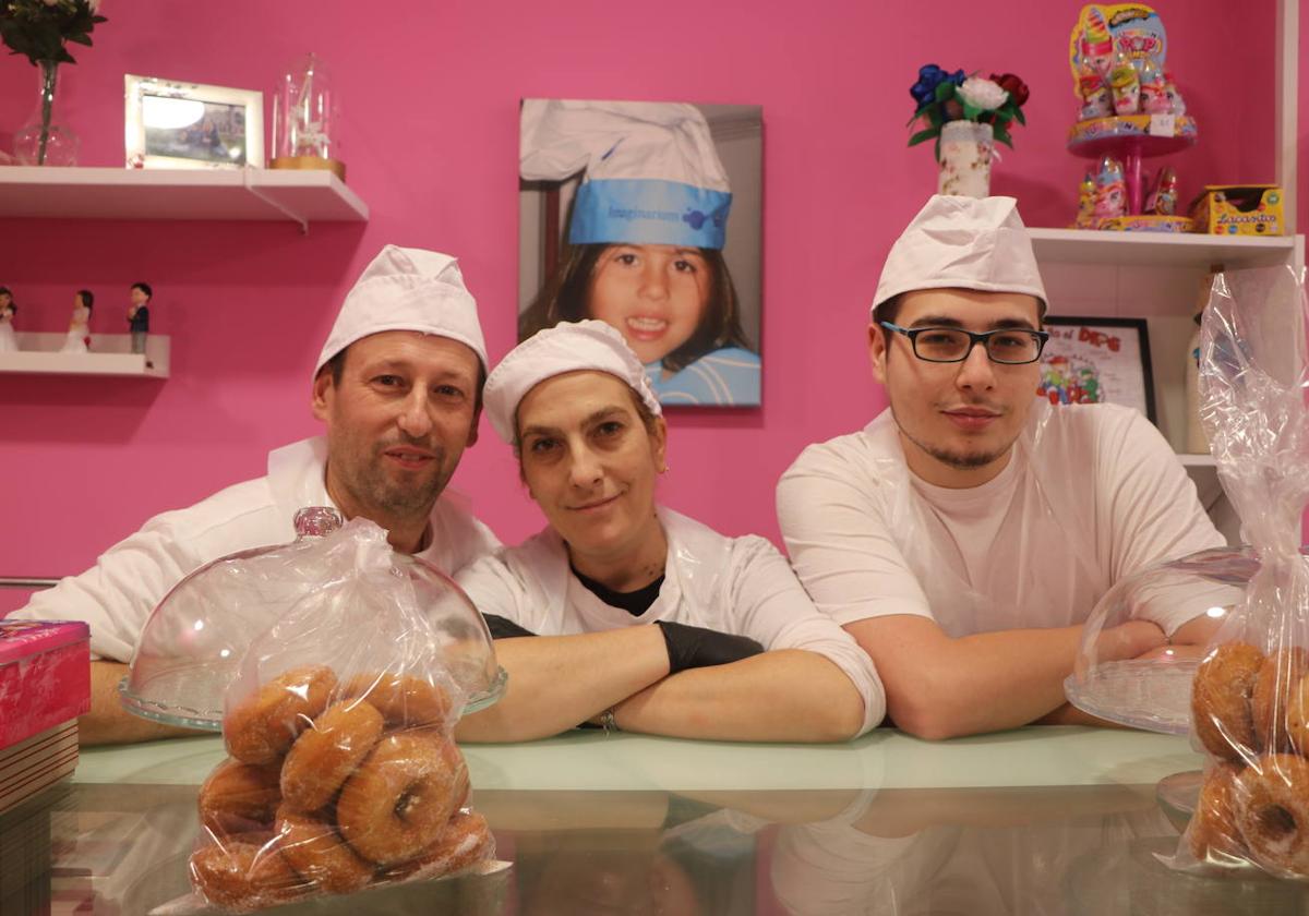 Ángel, Nieves y Rubén en el mostrador de la pastelería con una foto de Lucía al fondo.