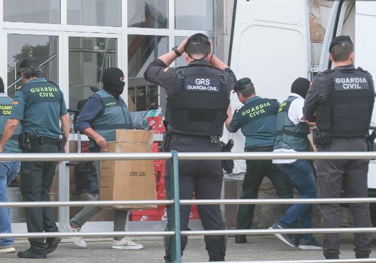 Agentes, algunos encapuchados, depositan en una furgoneta cajas con material incautado en la casa de uno de los detenidos, en Torrelavega.