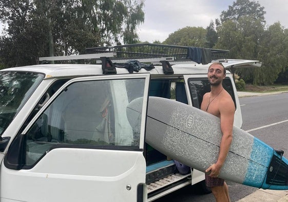 Álvaro con su tabla de surf en la furgoneta en la que vive en Australia.