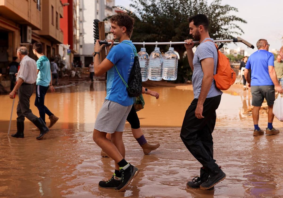 Voluntarios transportan agua en Paiporta, Valencia.