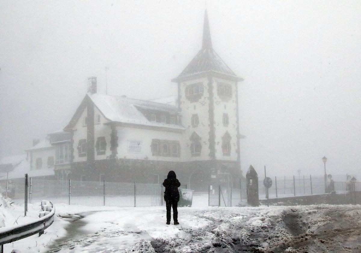 Una mujer realiza una fotografía al Parador de Pajares bajo la nieve.