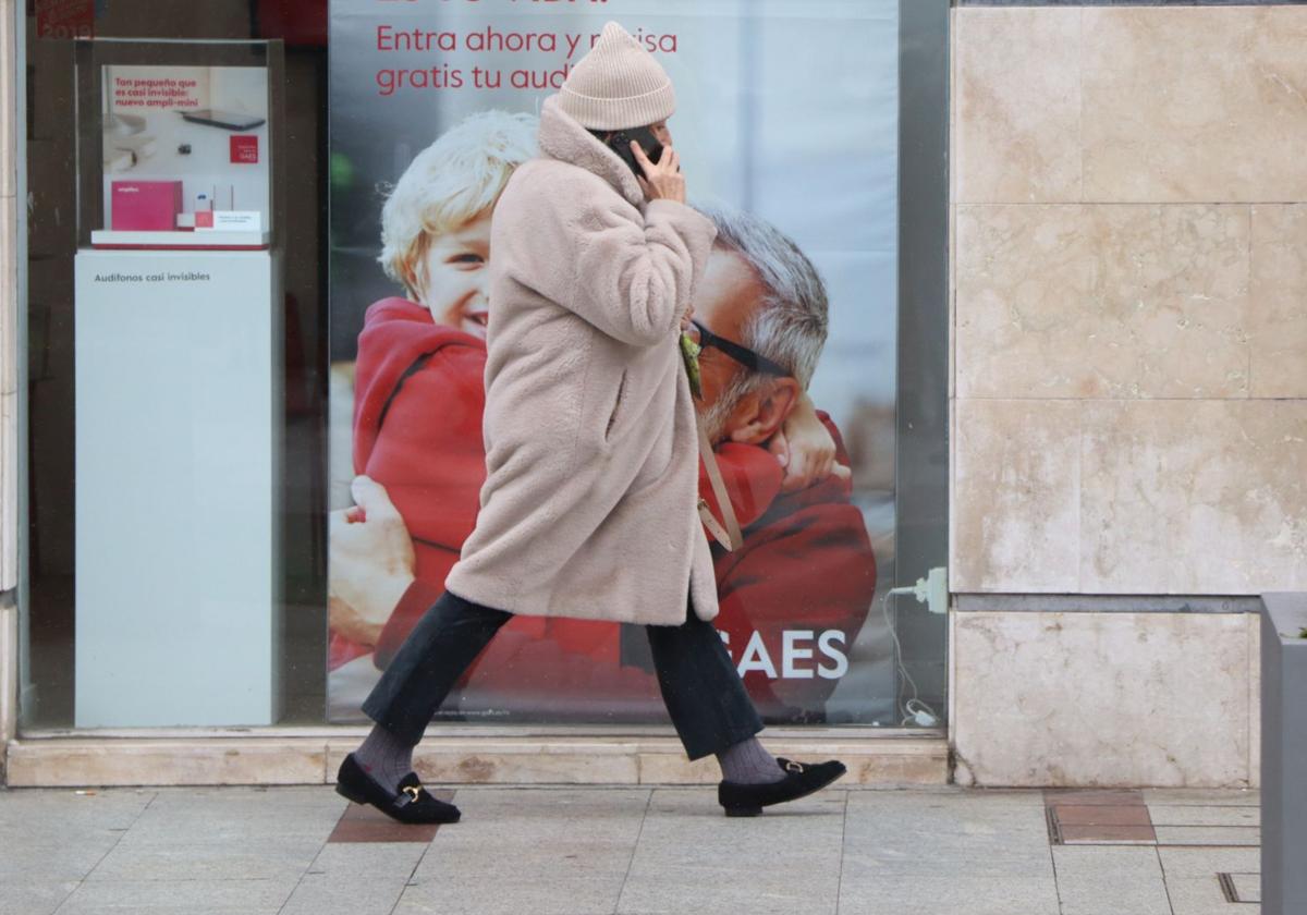 Una mujer camina abrigada por el centro de León.