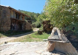 Una de las casas del pueblo y una fuente.