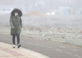 Una mujer camina abrigada por la ciudad de León.