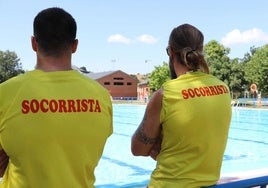 Dos socorristas vigilan una piscina.