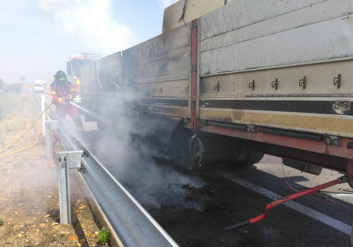 Un bombero de la Diputación de León sofoca el incendio en los bajos de un camión en la A-6 en León.