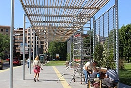 Varios trabajadores rematan la instalación de elementos en la pérgola bioclimática que hará las funciones de intercambiador de autobuses en la avenida Reyes Leoneses.