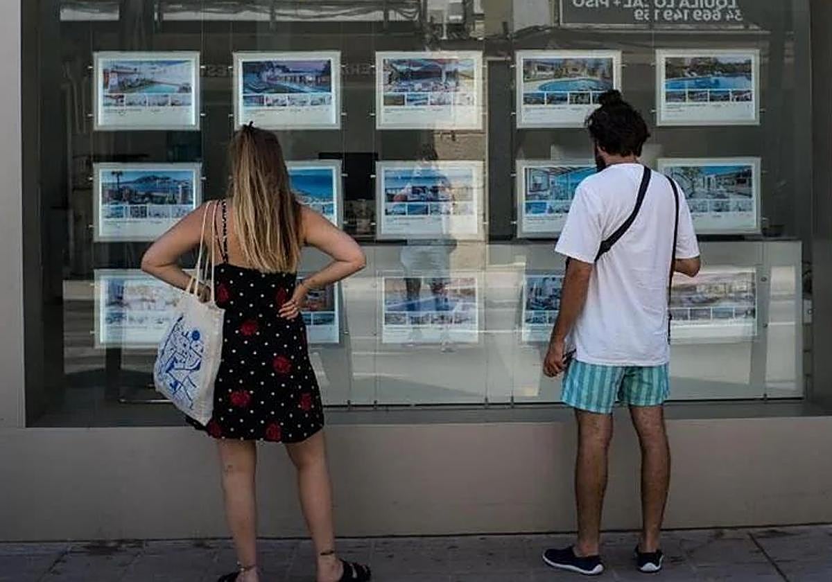 Dos personas revisan las opciones de alquiler de una inmobiliaria.