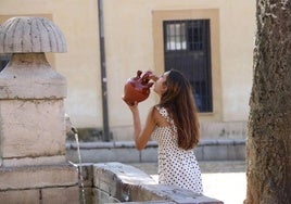 Una mujer bebe de una fuente en León.