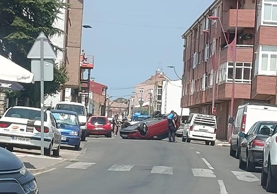 Un coche volcado corta un carril en una calle de Trobajo del Camino.