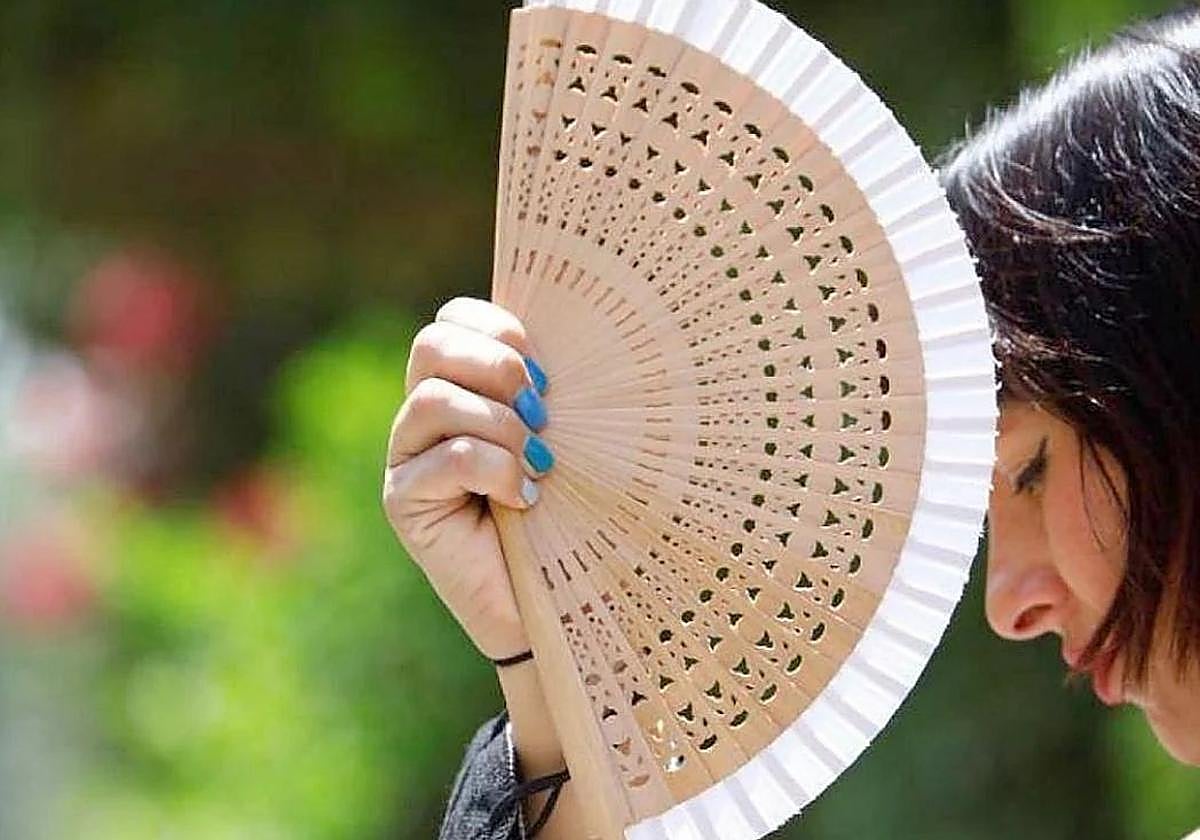 Una mujer se protege del sol con su abanico.