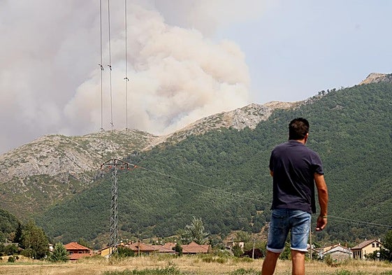 Un joven habla por teléfono en Boca de Huérgano y, al fondo, la columna de humo se levanta por Portilla.