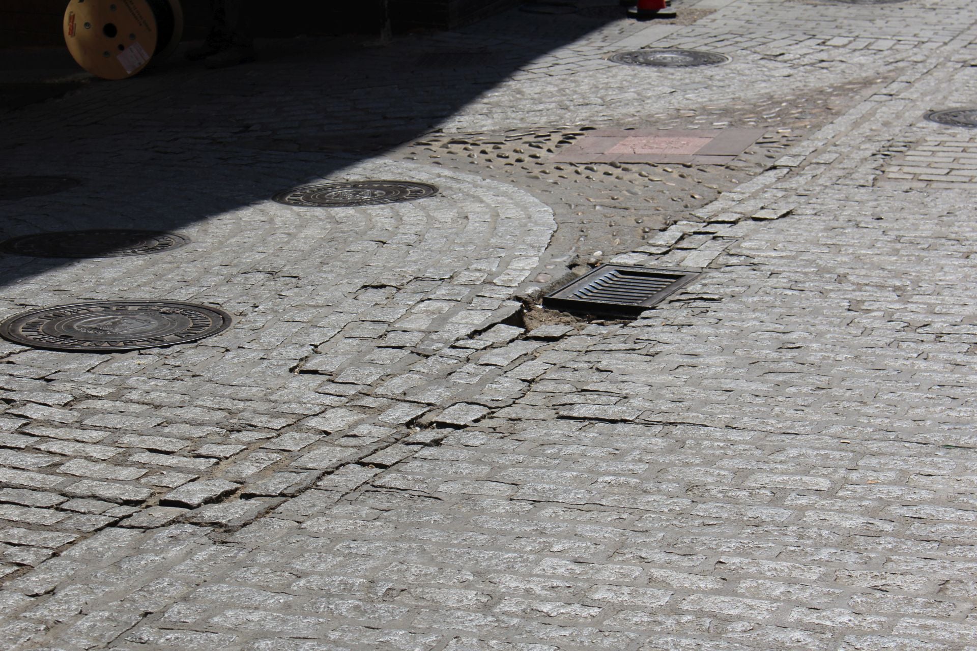 Imagen principal - Baches, tramos hundidos y ausencia de adoquines en la calle Santa Cruz.