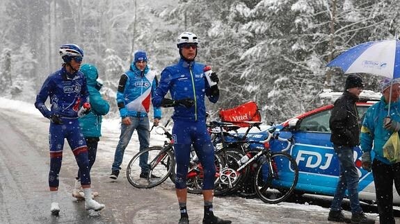 Varios ciclistas esperan mientras nieva. 