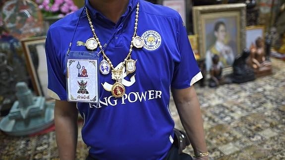 Un hombre muestra la camiseta y los amuletos del Leicester. 