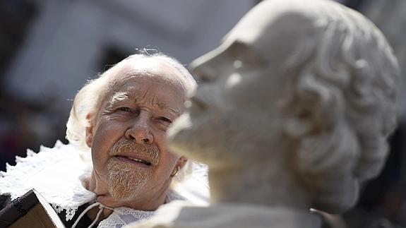 Un hombre caracterizado como Shakespeare contempla un busto del dramaturgo inglés.