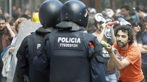 Un manifestante lanza agua a los antidisturbios de los Mossos d'Esquadra. 