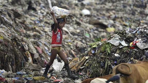 Una niña india recogiendo basura en un vertedero. 