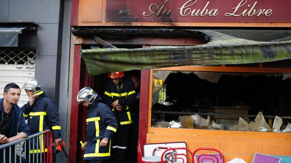 Los bomberos salen del local siniestrado.