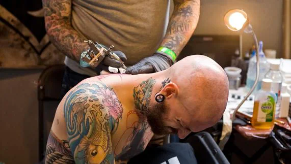 Un tatuador realiza un tatuaje.