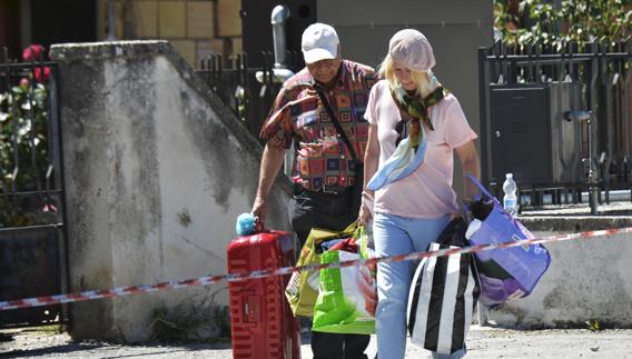 Dos personas trasladan sus pertenencias en Amatrice, la localidad más afectada por el terremoto.