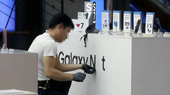 Un empleado quita las marca de Galaxy Note 7 en una tienda en Seúl.