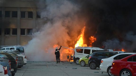 Un bombero extinguiendo el fuego provocado por un coche bomba hoy en Adana. 