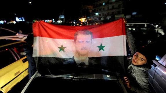 Un seguidor de El-Asad, con una bandera siria con su cara, en Alepo. 